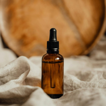Amber glass dropper bottle on a textured surface with a wooden plate in the background